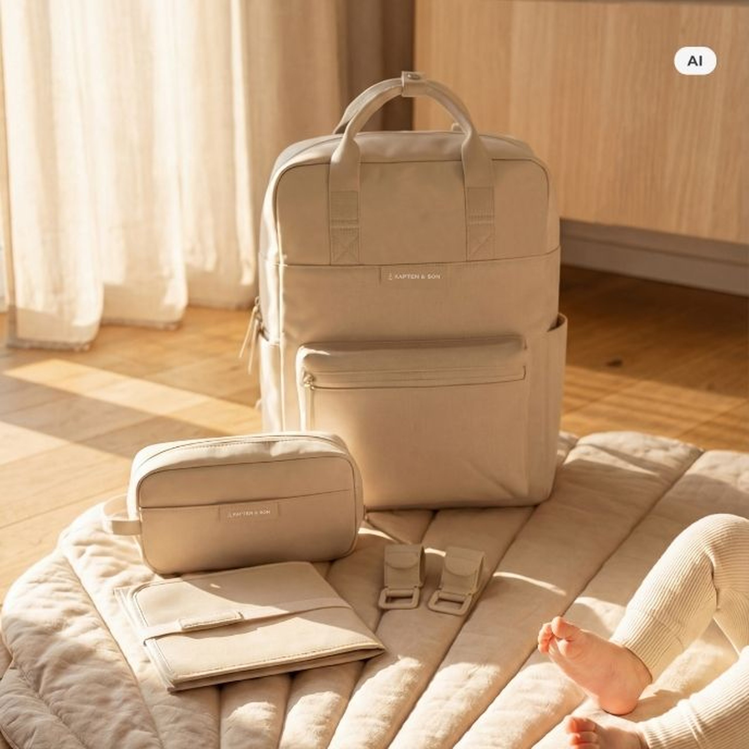 AI Generated Image: Ein cremefarbener Kapten & Son Rucksack mit passendem Kulturbeutel und Organizer auf einer hellen Unterlage, im Hintergrund ein Holzboden und ein helles Fenster mit Vorhang – rechts unten sind die Beine eines Babys zu sehen.