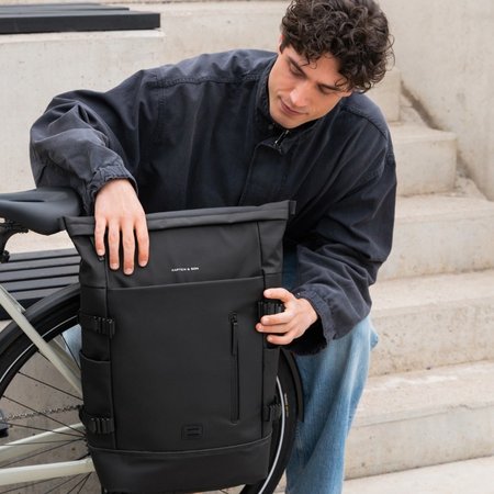 junger mann montiert rucksack am fahrrad