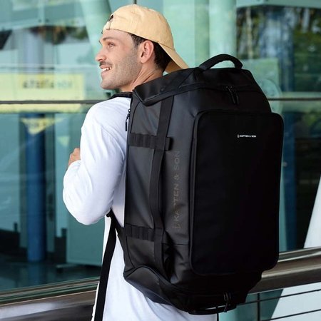 mann trägt großen reiserucksack von kapten and son am flughafen