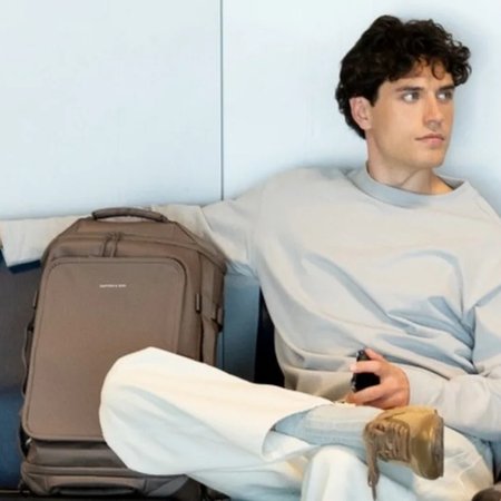 Man zit met een duffle bag bij de gate en wacht op zijn vlucht