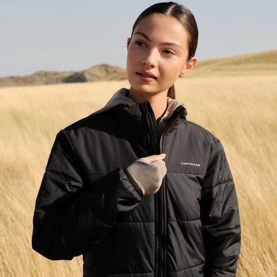 junge frau öffnet reißverschluss ihrer schwarzen puffer jacket