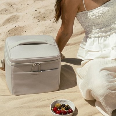 strandtasche von kapten and son liegt auf einer decke an einem sandstrand
