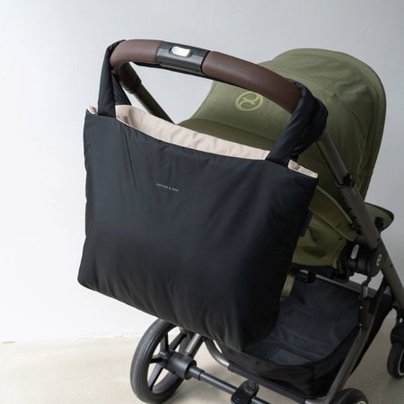 schwarze wickeltasche von kapten and son hängt über dem kinderwagen