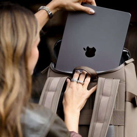 hand zieht laptop aus dem rucksackfach 