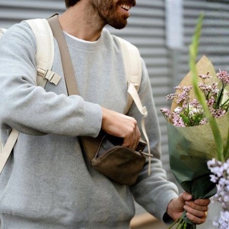 Man koopt bloemen en grijpt in zijn crossbody bag