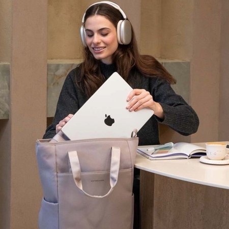 junge frau schiebt ihren laptop ins fach ihres business rucksacks