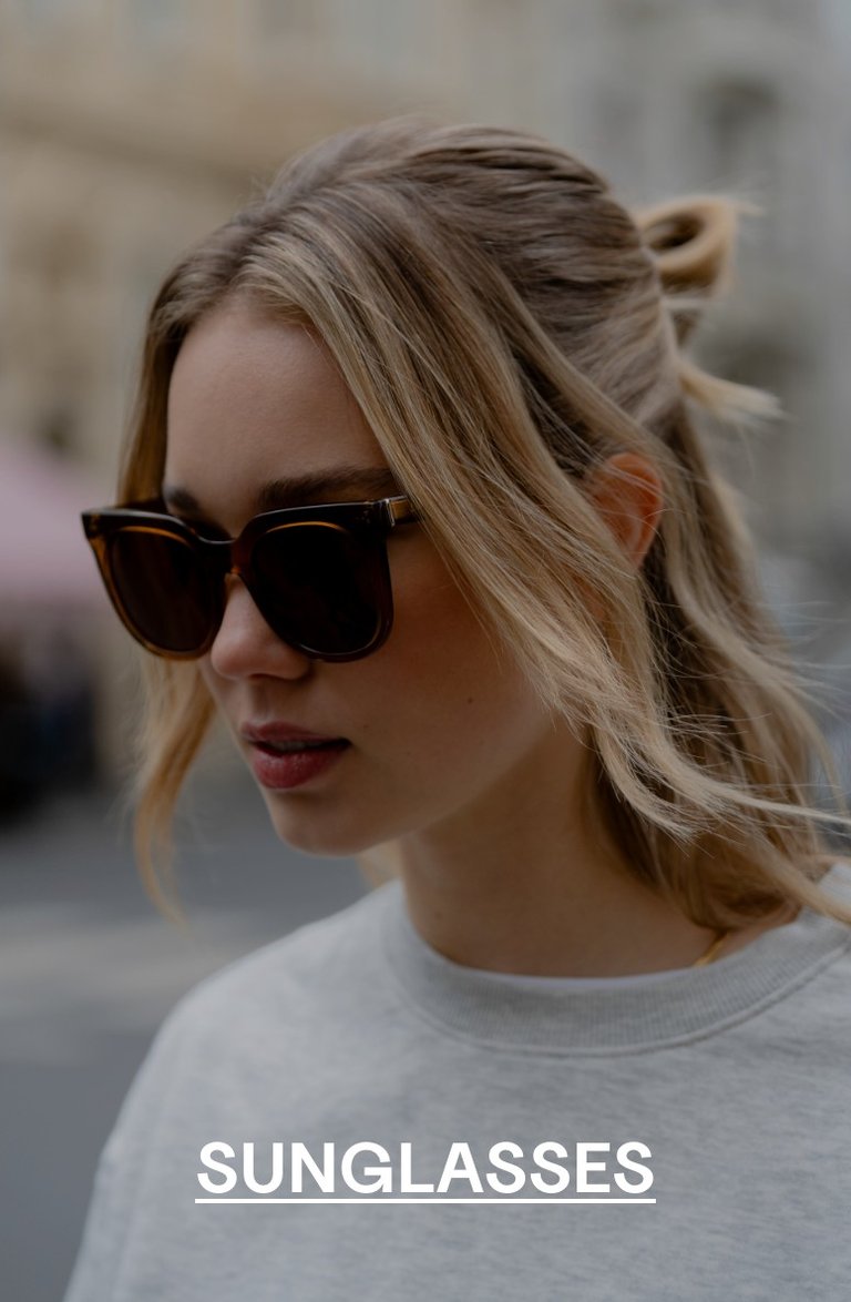Woman with blonde hair wearing tortoiseshell Kapten & Son sunglasses and a light grey sweatshirt, looking down – text overlay: "SUNGLASSES"