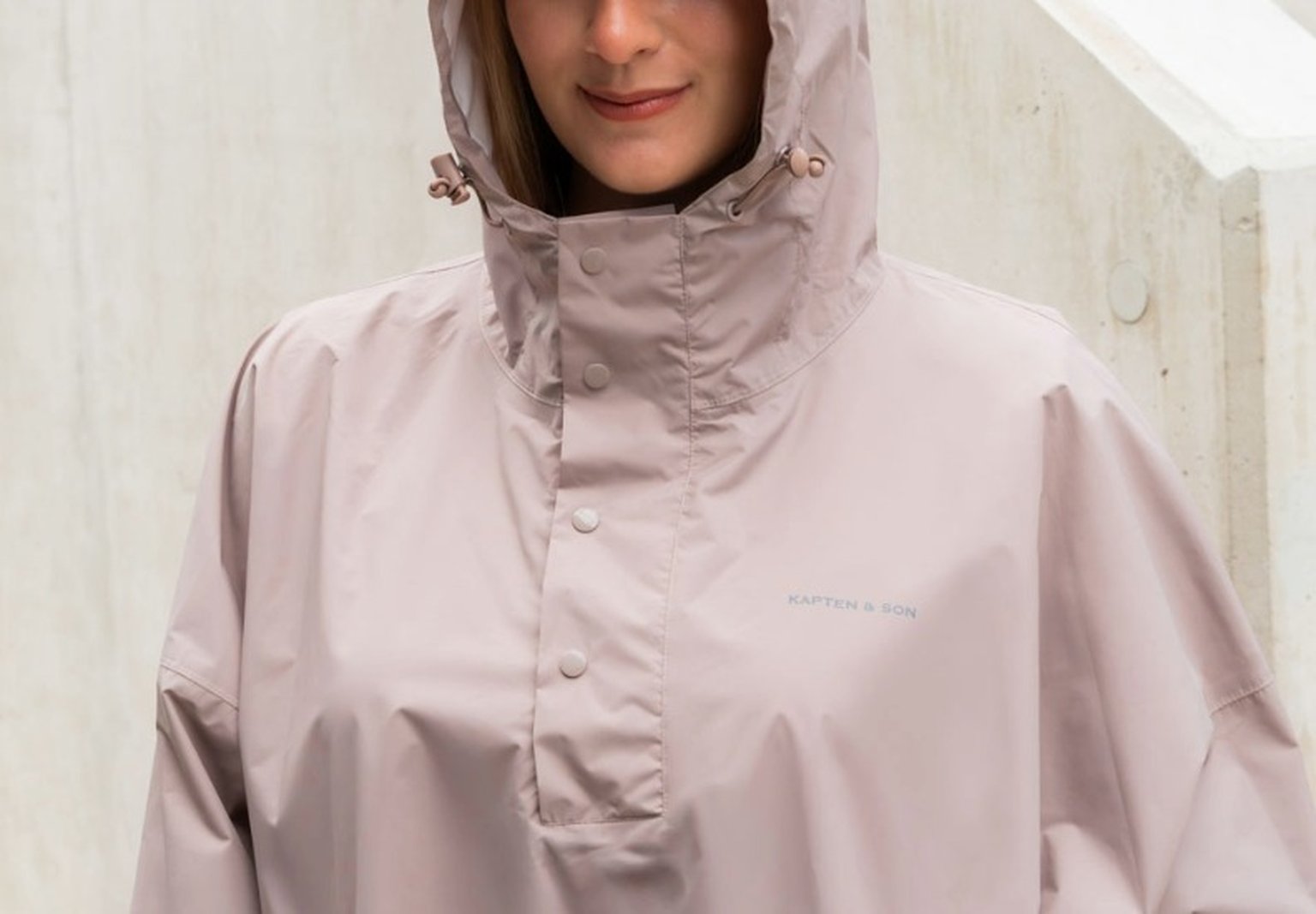 junge frau trägt pinken regenponcho von kapten & son