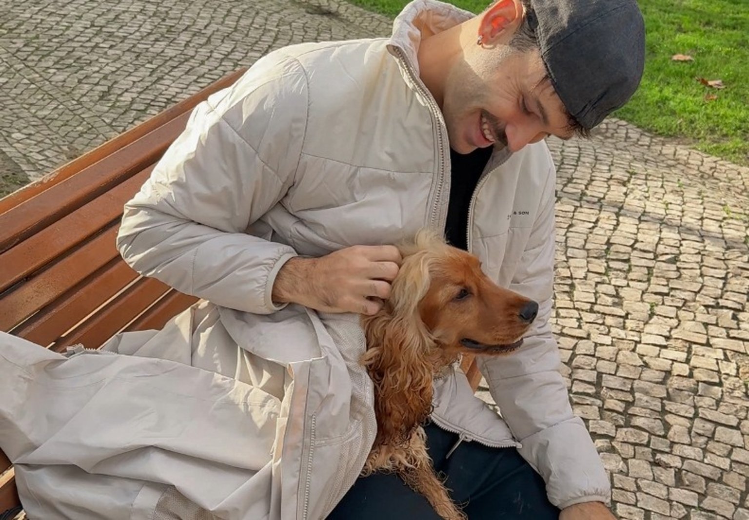 mann streichelt seinen hund und deckt ihn mit seiner kapten & son regenjacke zu