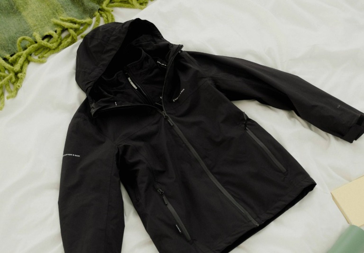 schwarze laufjacke liegt auf dem bett