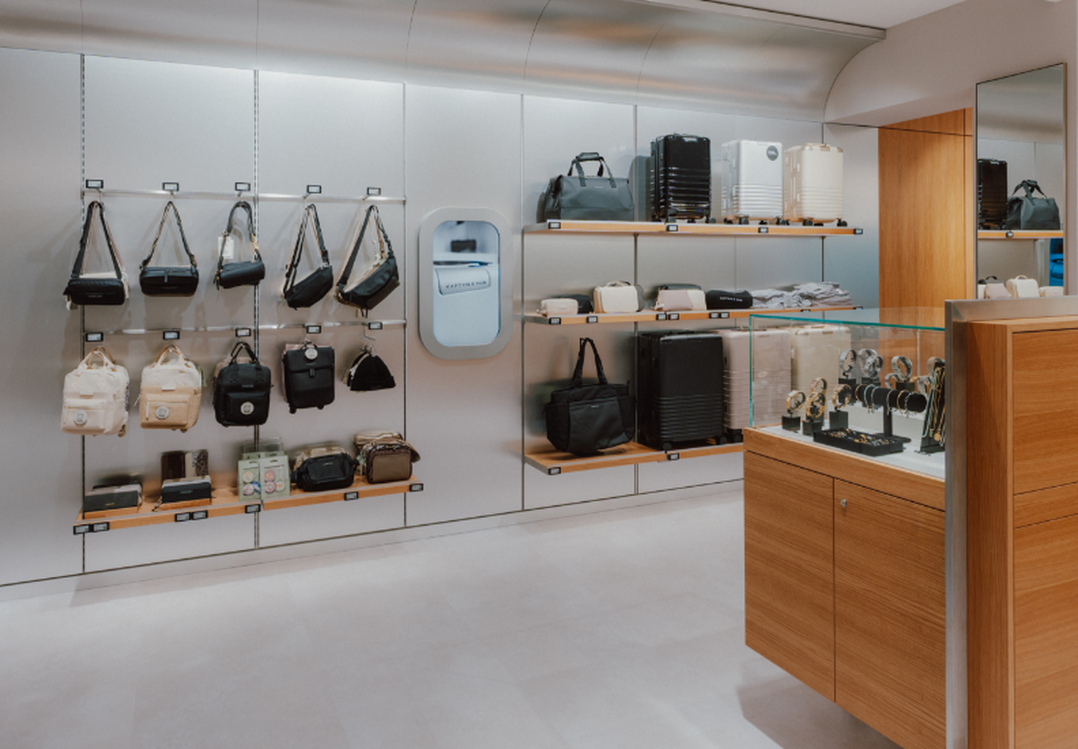Innenansicht des Kapten & Son Experience Stores – Wandregal mit Taschen, Rucksäcken und Accessoires, Regale mit Reisegepäck und Reisetaschen sowie eine Glasvitrine mit Uhren und Schmuck