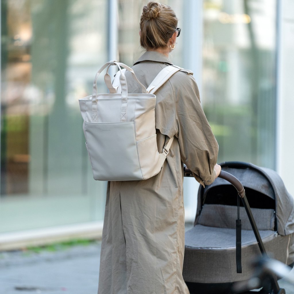 Mutter mit Kinderwagen und Lindby Wickelrucksack von Kapten and Son auf dem Rücken