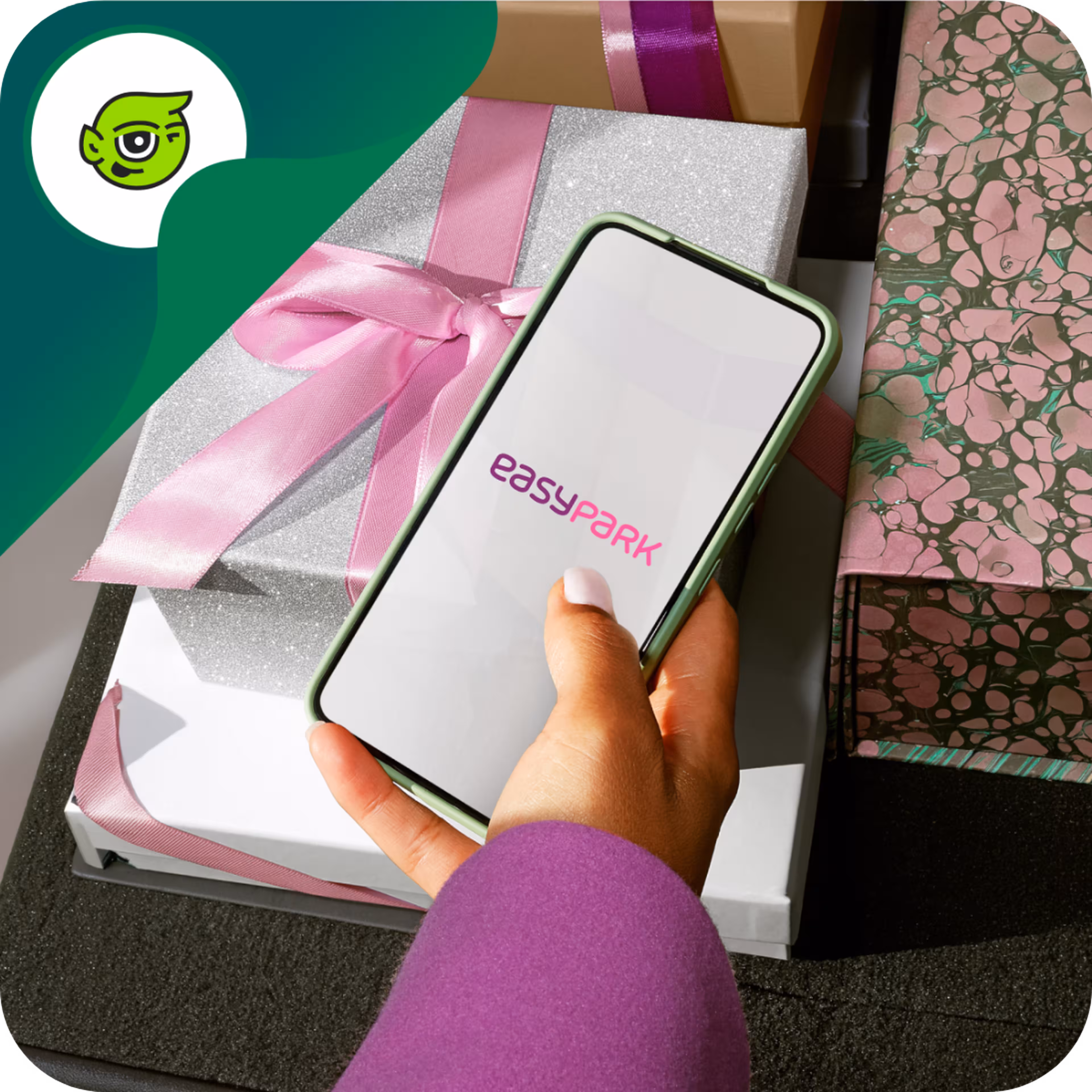 Hand holding a phone displaying "Easypark" app over gift boxes with pink ribbons.