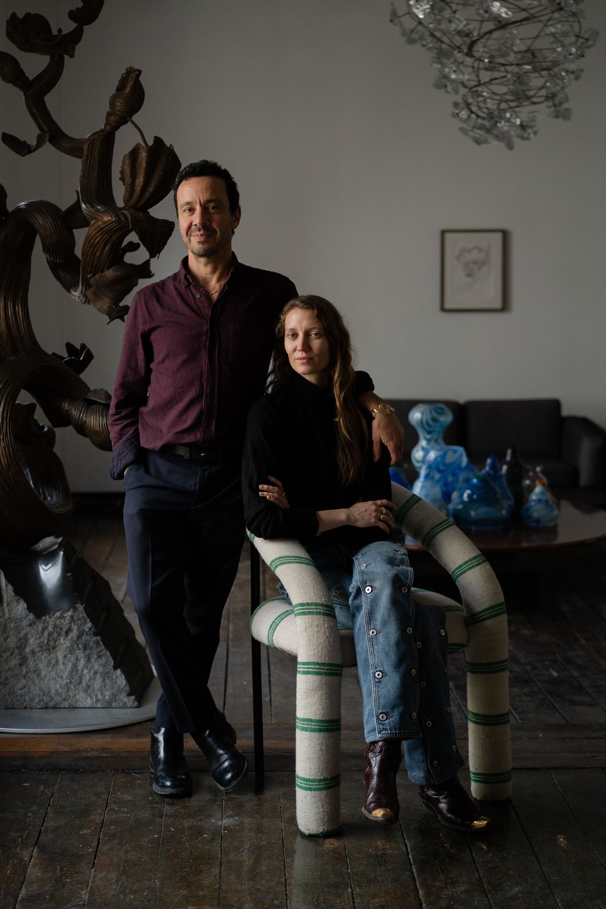 Portrait d’un homme et d’une femme dans un intérieur au style artistique et contemporain, entre sculptures et objets en verre soufflé.
