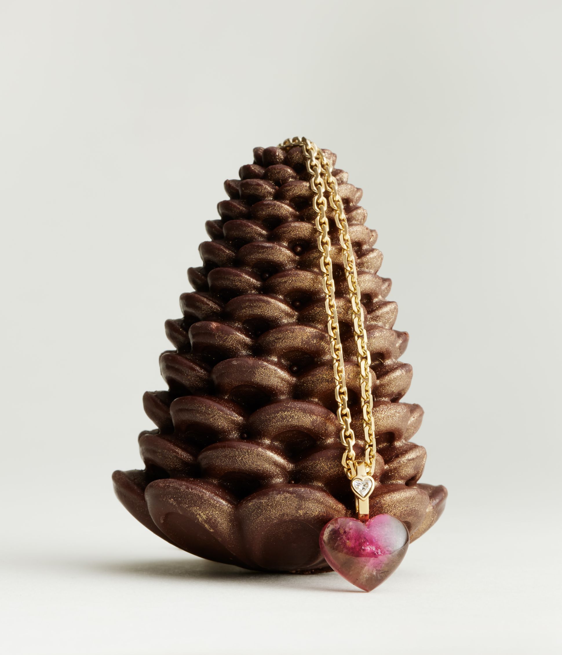 Pendentif Violette Joaillerie en forme de coeur sur une chaine en or accroché à une pomme de pain