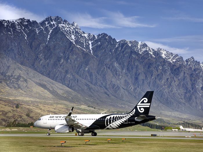 An Air New Zealand plane on a runway with mountains in the background