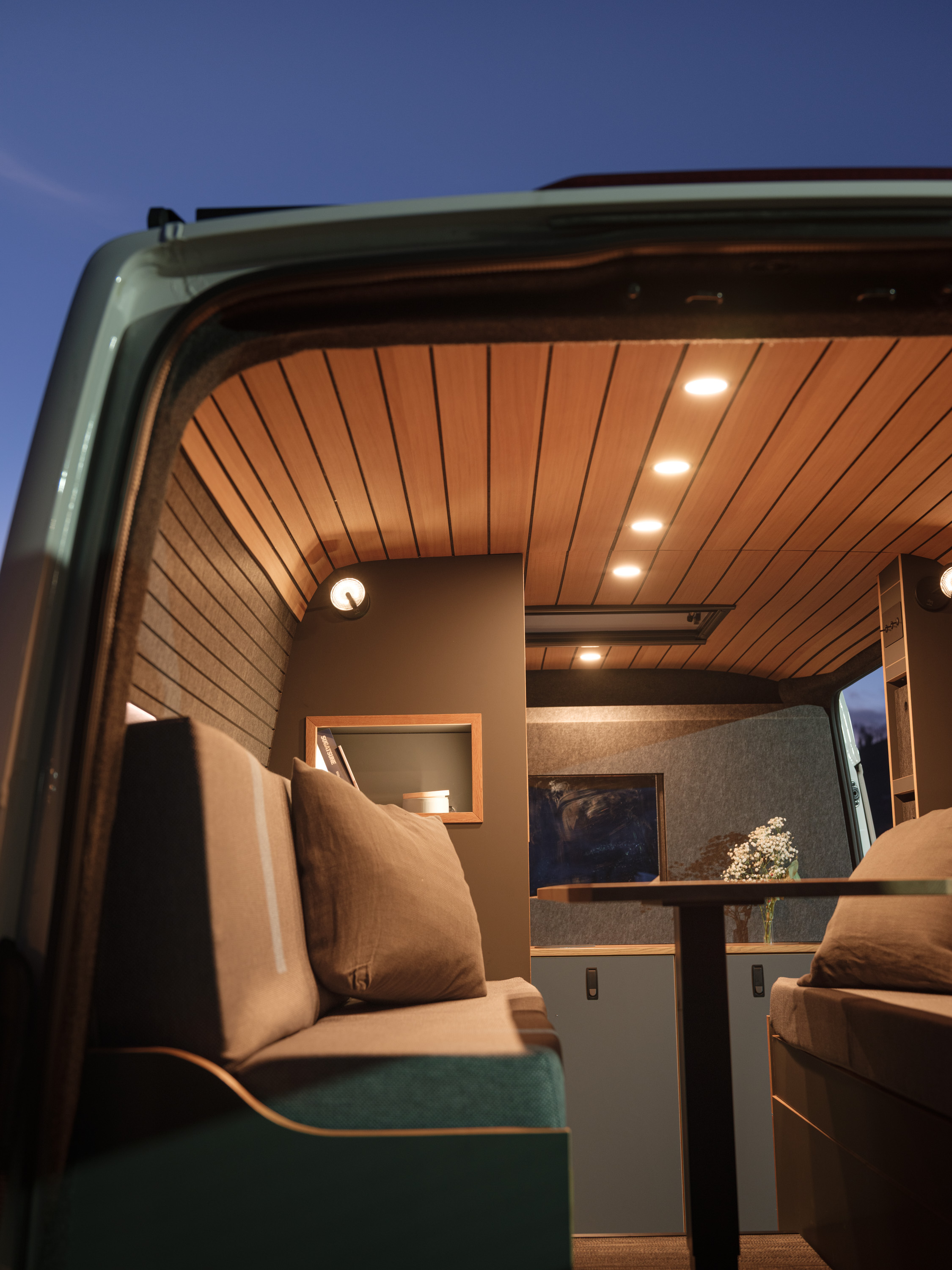 Campervan mit Innenbeleuchtung. leicht diffuse stimmung mit Warmweisser Beleuchtung. Tisch und Sitzbank in einem Campervan von cocoon Vans