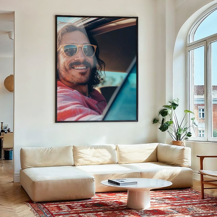 Großformatiges gerahmtes Acrylglasbild eines lächelnden Mannes im Auto, hängt über einem hellen Sofa im Wohnzimmer