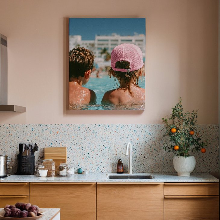 Leinwanddruck mit Urlaubsmotiv über einer Küchenzeile mit Terrazzo-Rückwand und Holzfronten in einer modernen Küche