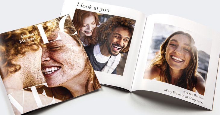 Fotobuch mit großem 'LOVE'-Cover-Design, Namen 'Emma & Michael' und aufgeschlagenen Innenseiten mit Liebestext und Paarfotos
