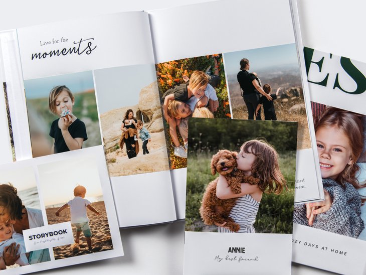 Mehrere Familien-Fotobücher mit Kinderfotos, u. a. beim Wandern, am Strand und mit einem Mädchen, das einen Hund küsst