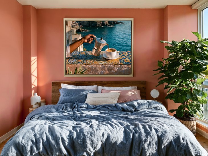 Gerahmter Leinwanddruck mit mediterranem Espresso-Motiv über einem Bett in einem Schlafzimmer mit terrakottafarbenen Wänden