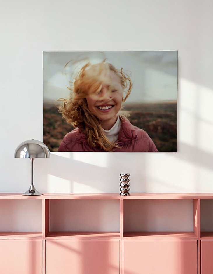 Leinwanddruck im Querformat 60 × 45 mit lachendem Mädchen in rosa Jacke über einem rosa Sideboard mit Designerlampe