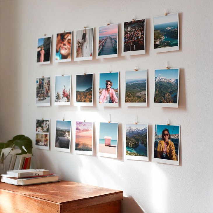 Fotowand mit zahlreichen Fotoabzügen in verschiedenen Formaten, mit Holzklammern an der Wand befestigt