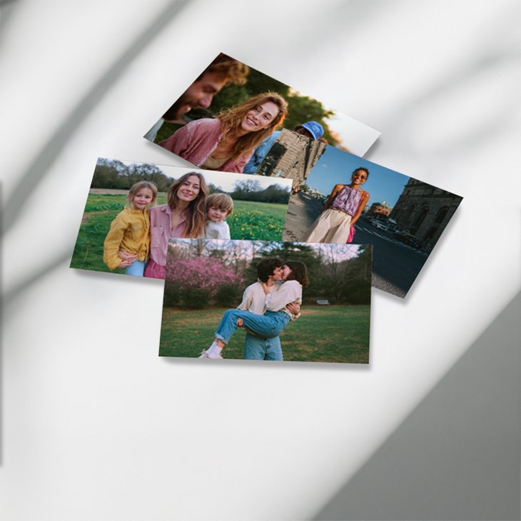 Vier Fotoabzüge mit Familien- und Pärchenmotiven locker übereinander auf einem sonnigen Untergrund