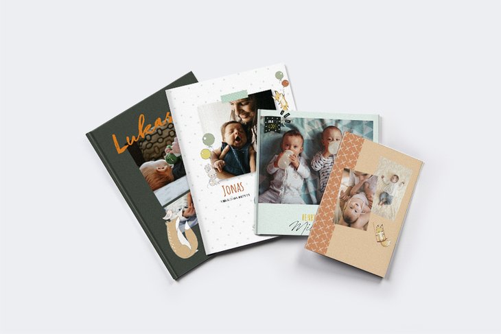 Vier gestaffelt aufgefächerte Baby-Fotobücher in unterschiedlichen Formaten mit Babyfotos und Namen auf dem Cover