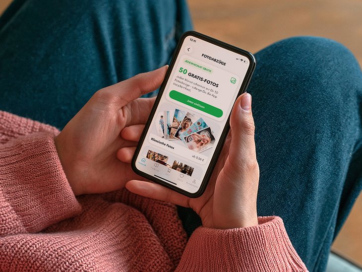 Frau zeigt Handy mit der MYPOSTER App
