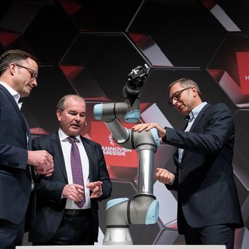 Dr. Jürgen Köckler, Per Thöresson und Jürgen von Hollen mit einem UR-Roboter während der Pressekonferenz