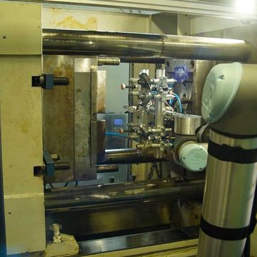 Der cobot neigt die Spritzgussmaschine. Dank einer Mehrfachgreifvorrichtung positioniert er die Druckmännchen und nimmt die vorgedruckten Artikel in einem einzigen Schritt auf