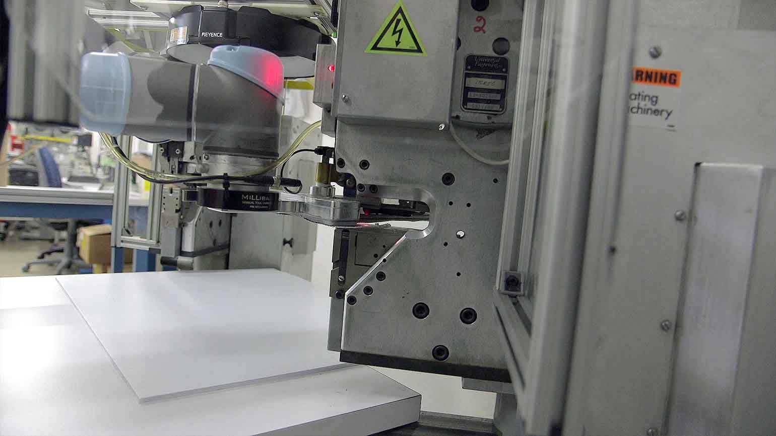 Arizona 회사는 5개의 수컷 스냅이 삽입된 스냅 세트 기계를 통해 협동로봇이 이동하는 사전 절단된 직물 재료를 픽업하도록 첫 번째 UR5를 프로그래밍한 다음 5개의 암 스냅이 추가되는 두 번째 기계로 이동합니다.