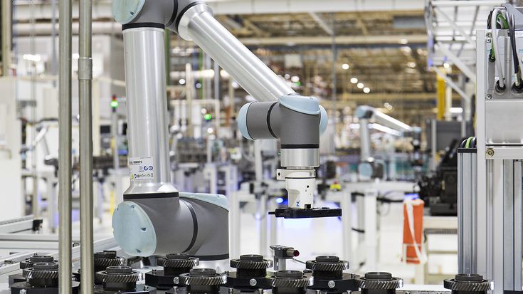 Industrial Universal Robots collaborative robot (cobot) performing automated pick-and-place tasks on a production line, showcasing flexible UR+ ecosystem integration for smart manufacturing applications.