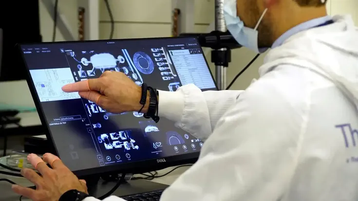 Técnico analisa peças e dados em tela sensível ao toque, ilustrando processos do sistema Just in Time na produção