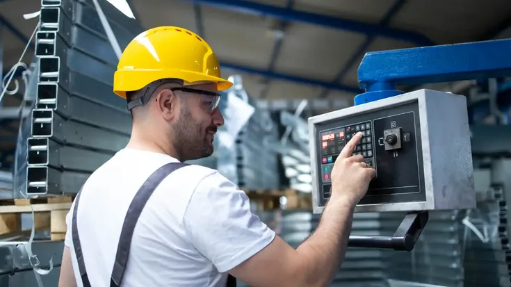 Operario configurando maquina industrial, representando el concepto de MTBF mean time between failures en mantenimiento.