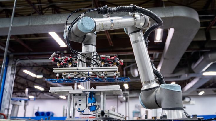 Collaborative robot moving a large workpiece with a vacuum gripper in an industrial manufacturing environment, demonstrating the impact of tooling and payload center of gravity on robot performance.