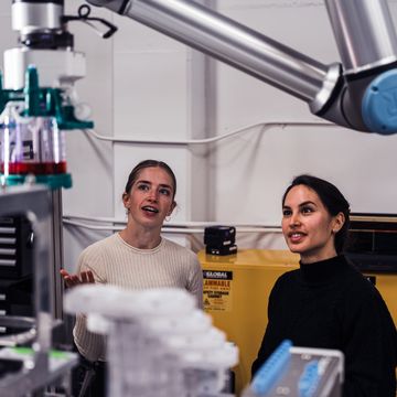 Two MultiplyLabs scientists observing a robotically automated process in the lab