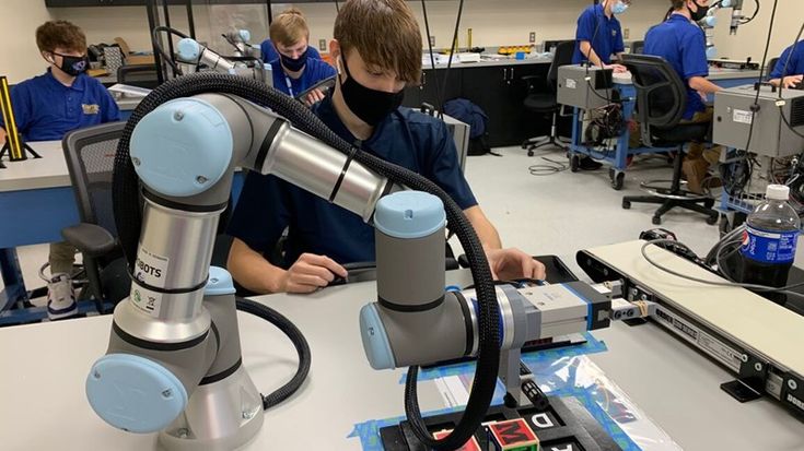 Students in a classroom work with a Universal Robots collaborative robot arm for hands-on robotics training.