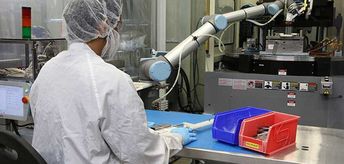 Na Dynamic Group, um cobot lida com um ciclo de injeção de máquina completo para um dispositivo médico com componentes extremamente sensíveis ao calor: ele pega e insere “molduras de livros” que seguram as peças a serem moldadas na máquina de molde por injeção, transportam as unidades para dispositivos de corte, colocam a parte na frente do operador humano para a próxima etapa e, finalmente, apertam um botão para começar o ciclo novamente.