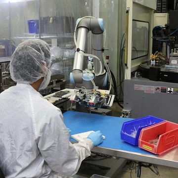 Um robô colaborativo UR5 da Universal Robots trabalha alimentando um robô cartesiano na Dynamic Group.