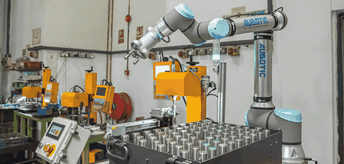 Dieser elektrische 3-Finger-Greifer umschließt runde Metalteile durch eine Drehbewegung.