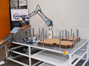 Der mit einem Saugnapfgreifer ausgestattete cobot holt die unverformte Kappe