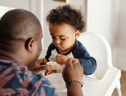 a father helping his son eat his lunch