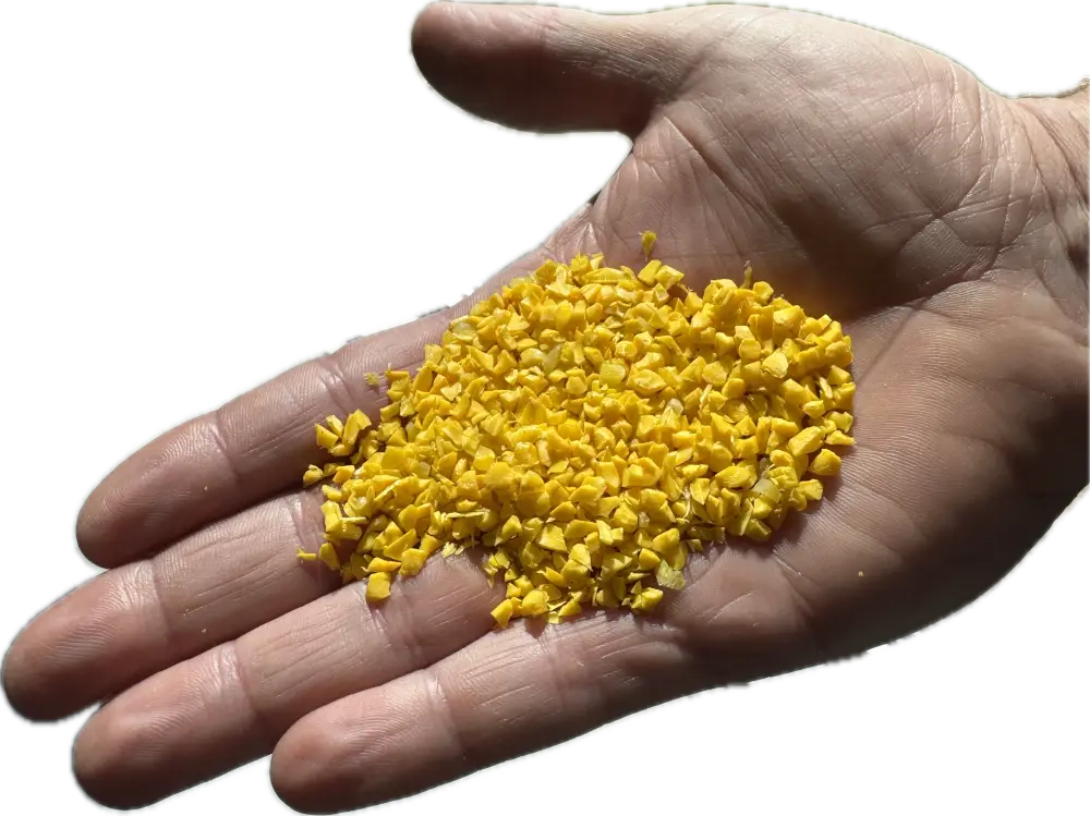 A hand holding a small pile of bright yellow plastic granules, against a white background.
