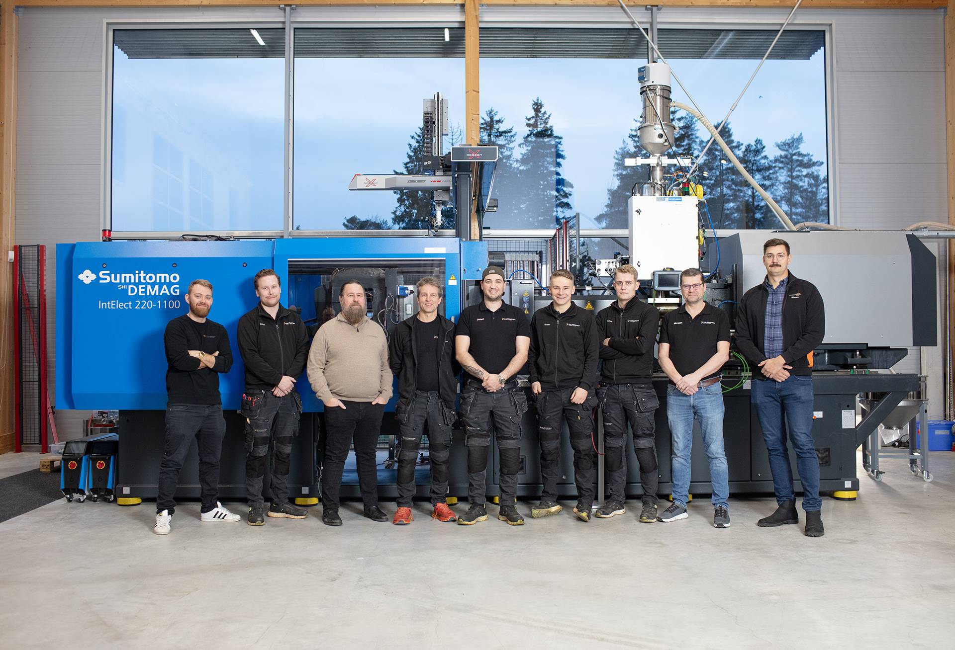 Team of K.D. Feddersen Service technicians in front of a Sumitomo Demag Injection moulding machine