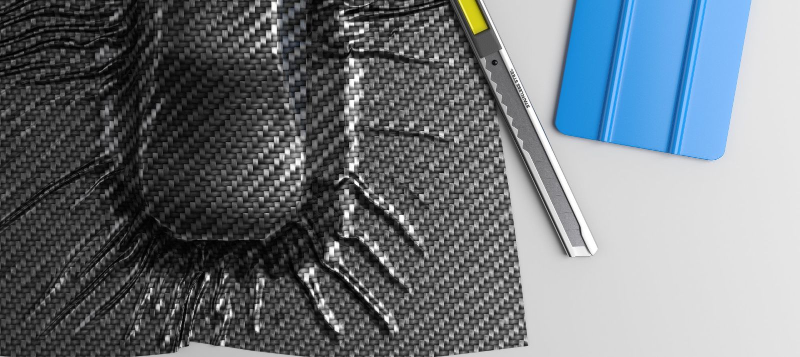 Kohlefaserplatte mit Universalmesser und blauem Rakel auf weißem Untergrund.