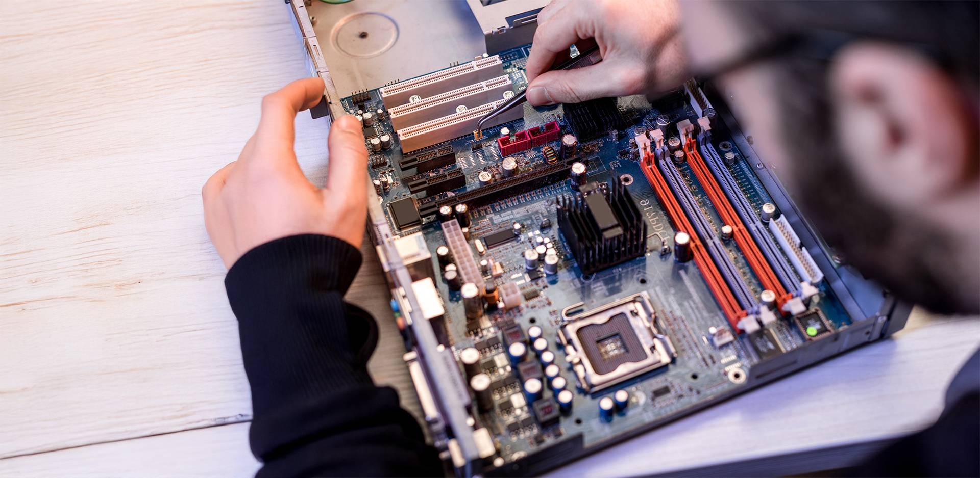 Person working on an open computer case and installing components on the motherboard.