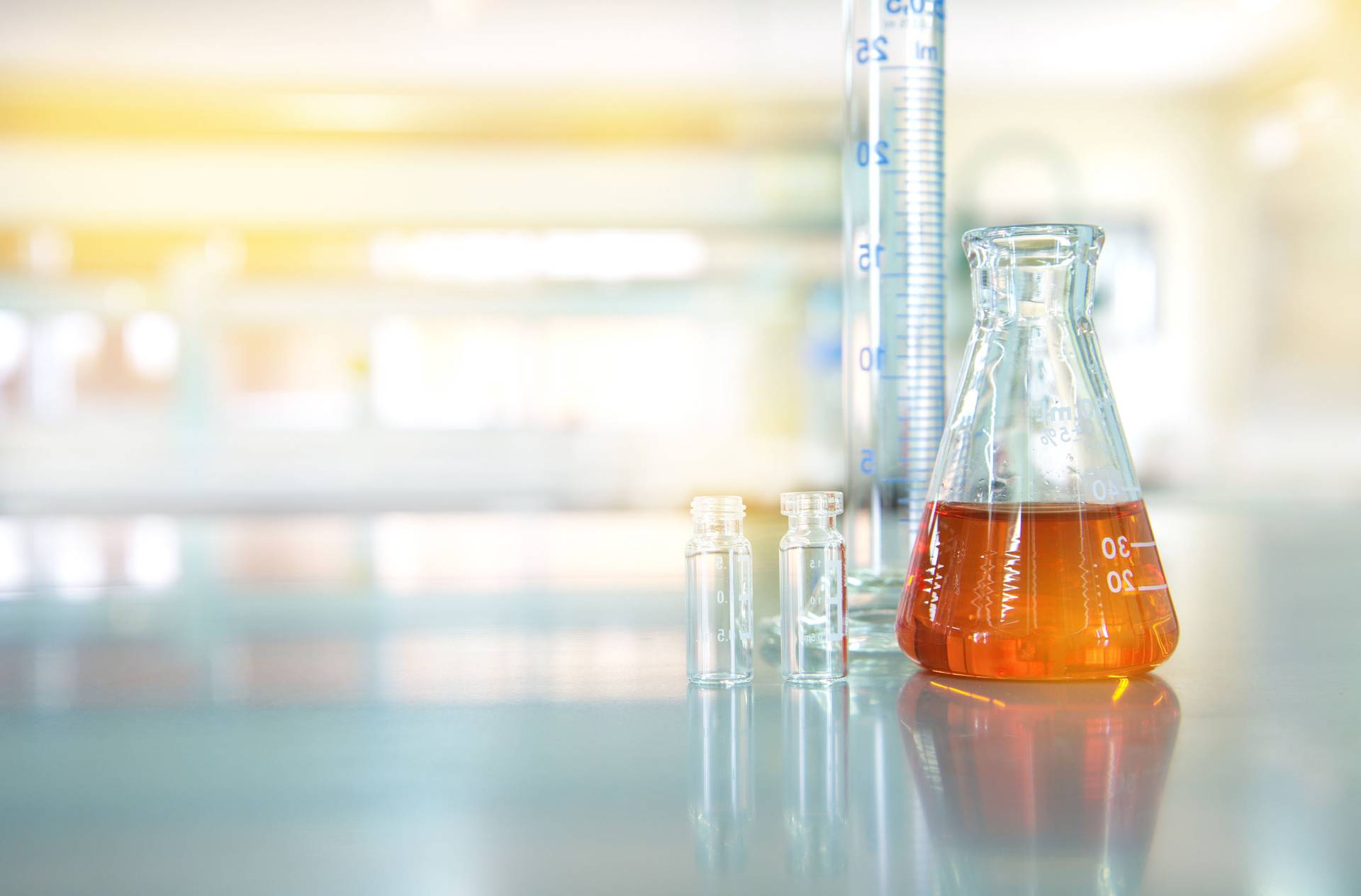 orange liquid in glass flask with cylinder vial in chemical science technology  laboratory background